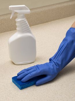 Cleaning a counter top wearing gloves and using a special spray
