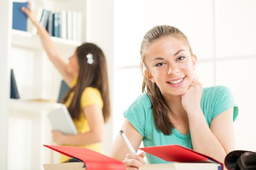 Beautiful teenage girl learning in the library