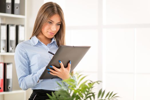 Beautiful Businesswoman with documents standing in the office.