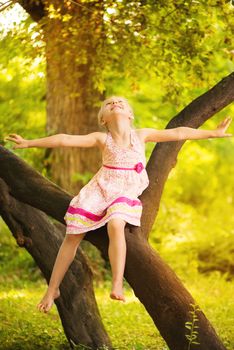 Cute little girl having fun on the tree in the park