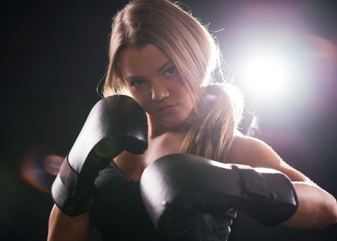 Portrait of Young beautiful boxing girl is giving a croshe punch.