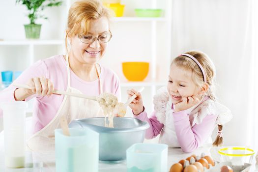 Beautiful happy grandmother learning her granddaughter Baking in a kitchen. 