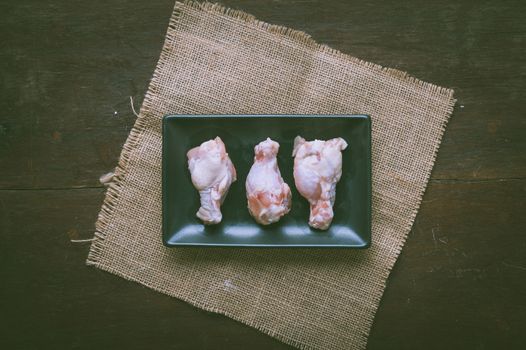 Preparation for cooking in home kitchen. Chicken wings in ceramic dish on wood table with vintage filter effect