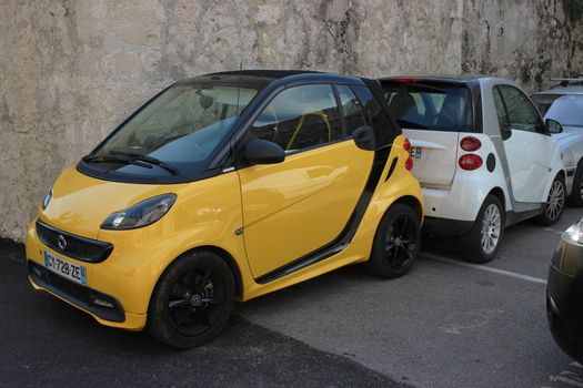 Saint-Paul-de-Vence, France - March 22, 2016: Yellow Smart Fortwo Cityflame and White Smart Fortwo Parked in the Street of Saint-Paul-de-Vence, France