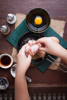Preparation for cooking in home kitchen. Woman hand mixing ingredients with chicken wings