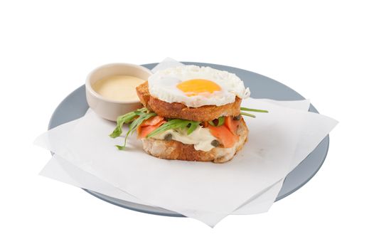 Grilled sandwich with bacon and fried egg in grey dish isolated on white background with clipping path