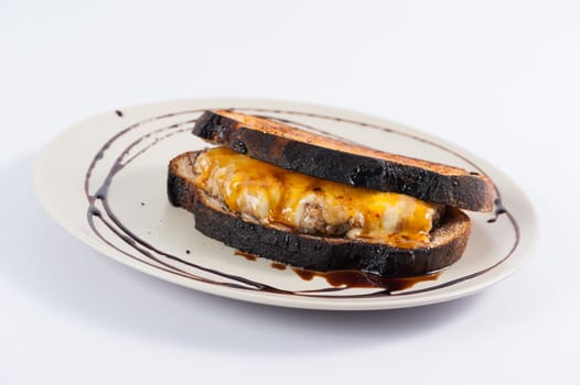 Toasted sandwich with various types of  cheese and beef in ceramic dish