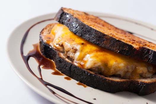 Toasted sandwich with various types of  cheese and beef in ceramic dish
