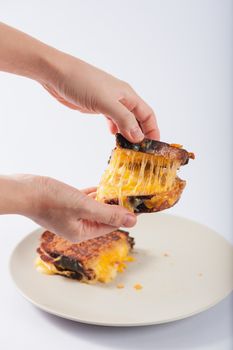 Toasted sandwich with various types of  cheese in ceramic dish. Woman hand try to open shell to show cheese inside.