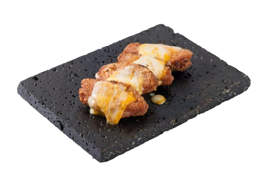 Deep fried chicken wings dressed with various types of cheese on black stone plate isolated on white background with clipping path