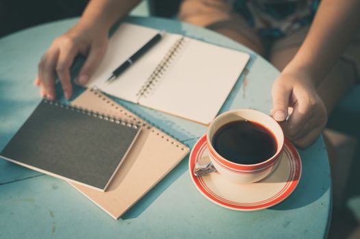 Woman left hand holding coffee cup during coffee break in cafe with morning scene and vintage filter effect