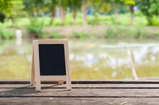 Small A-frame blackboard with blank area for text or message on rustic wood table in morning time