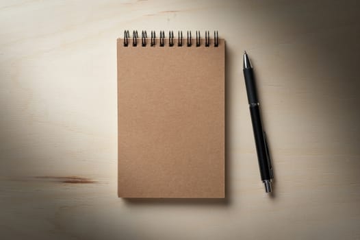 Closed notebook with blank area on front cover on wood table with low key scene