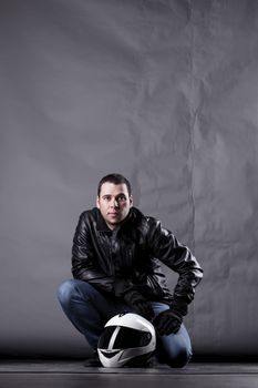 motorist with a helmet, leather jacket and jeans, on grunge background with harsh lighting