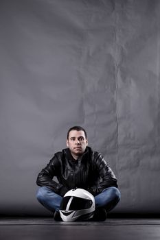 motorist with a helmet, leather jacket and jeans, on grunge background with harsh lighting