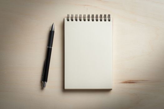 Opened notebook with blank area for text or message and pen on wood table with low key scene