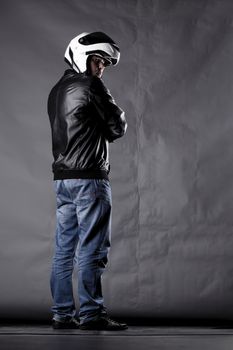 motorist with a helmet, leather jacket and jeans, on grunge background with harsh lighting