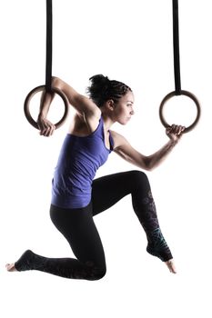 fit girl girl exercising on gymnast rings, against white background