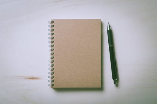 Closed notebook with blank area on front cover on wood table with vintage filter effect