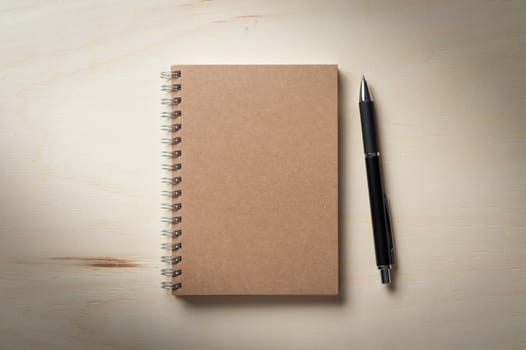 Closed notebook with blank area on front cover on wood table with low key scene