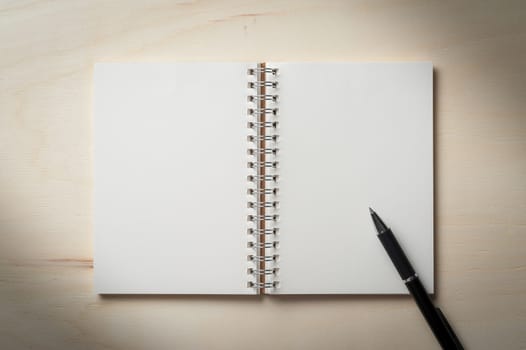 Opened notebook with blank area for text or message and pen on wood table with low key scene