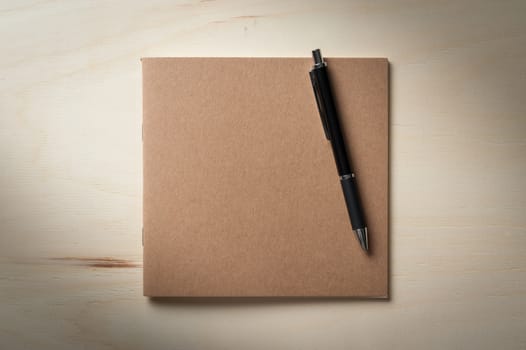 Closed sketch book with blank area on front cover on wood table in morning time with low key scene