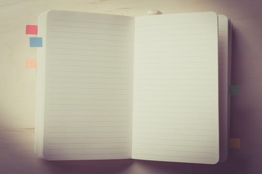 Opened notebook with blank area for text or message on wood table with vintage filter effect