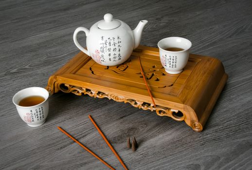 Exotic tea still-life contains teapot, cups, insence and tea sea.