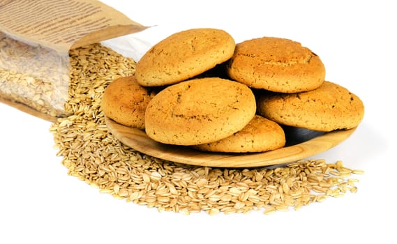 Oatmeal cookies on a wooden plate and a paper bag with crumbled oat flakes, isolated on white background.