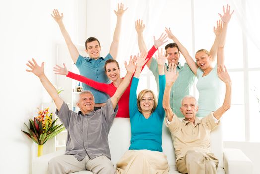 Big cheerful family enjoying at home and rejoices with open arms 