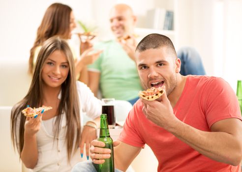 Young couple enjoying to eating pizza together at home party.