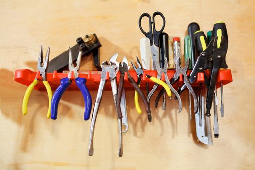 Workshop tools pliers clamps on the stand on the wall, a pair of scissors, bender, screwdrivers, power indicator, an adjustable wrench. 