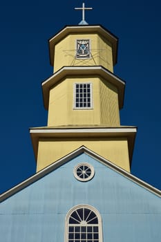 Yellow and blue facade of the historic 19th century wooden church in Conchi on the island of Chiloé in southern Chile.