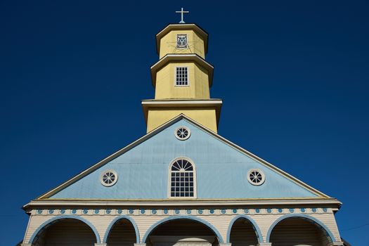 Yellow and blue facade of the historic 19th century wooden church in Conchi on the island of Chiloé in southern Chile.