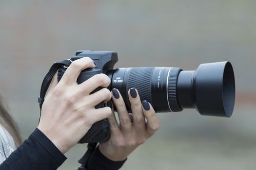 girl with beautiful manicure holds single-lens reflex camera