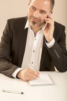 Attractive man talking on the telephone with his business partner. At the office, white background