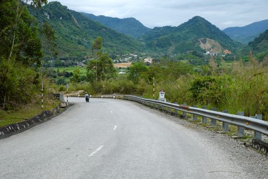 Scene on Ho Chi Minh trail on clouds day, house on hill, danger terrain with mountain pass, people cross stream, life on highland Vietnam among green forest