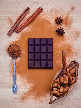 Brown chocolate powder in spoon , Roasted cocoa beans in the dry cocoa pod fruit and dark chocolate setup on wooden background.