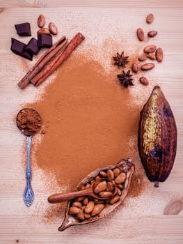 Brown chocolate powder in spoon , Roasted cocoa beans in the dry cocoa pod fruit and dark chocolate setup on wooden background.