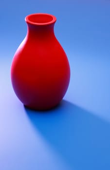 Nice red ceramic vase on blue background with long shadow