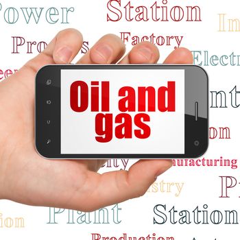 Industry concept: Hand Holding Smartphone with  red text Oil and Gas on display,  Tag Cloud background
