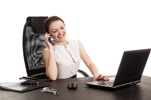 the business woman sits at office table with the laptop and speaks by phone