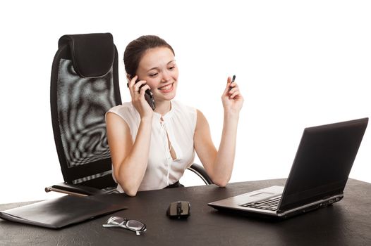 the business woman sits at office table with the laptop and speaks by phone