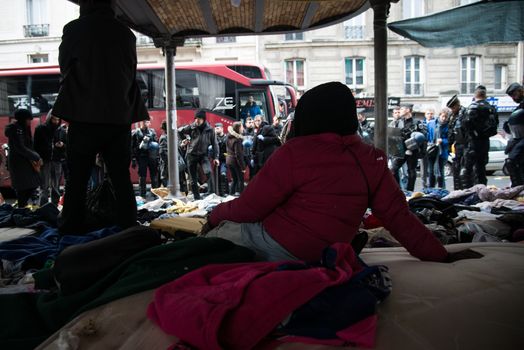 FRANCE, Paris : Two people stand as they are evacuated by police officers and gendarmes from a makeshift camp under the Stalingrad railway station in Paris on March 30, 2016 where hundreds of migrants and refugees were established for three weeks.Launched at 6:20 (4:20 GMT) by State services, the Town of Paris and police headquarters, the operation ended peacefully two hours later. It is the 18th operation of this kind organised in the French capital since June 2015. 