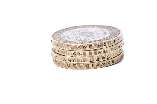 stack of british 2 pound coins showing motto standing on the shoulders of giants