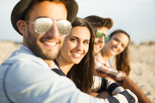 Friends sitting at the beach and having fun