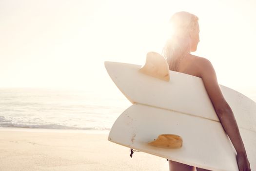 Beautiful young woman holding her surfboard after a day of surf
