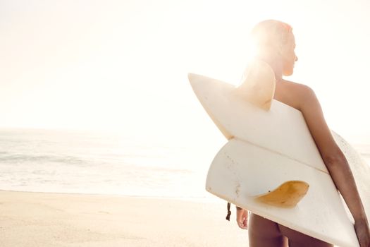 Beautiful young woman holding her surfboard after a day of surf