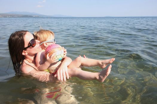 Mother and daughter in same bikinis enjoying and playing in the sea