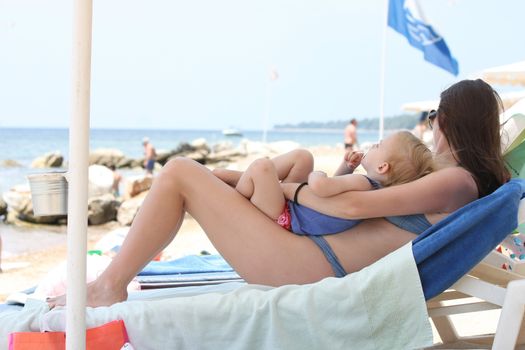 Cute baby girl with her mother sleeping on the beach 